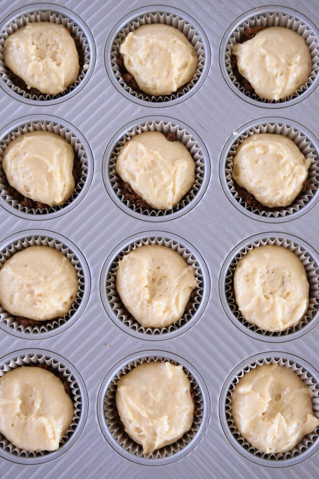 Muffin tin filled with muffin batter, crumble and more muffin batter.