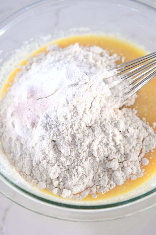 Glass bowl with flour, salt and baking soda on top of wet batter.