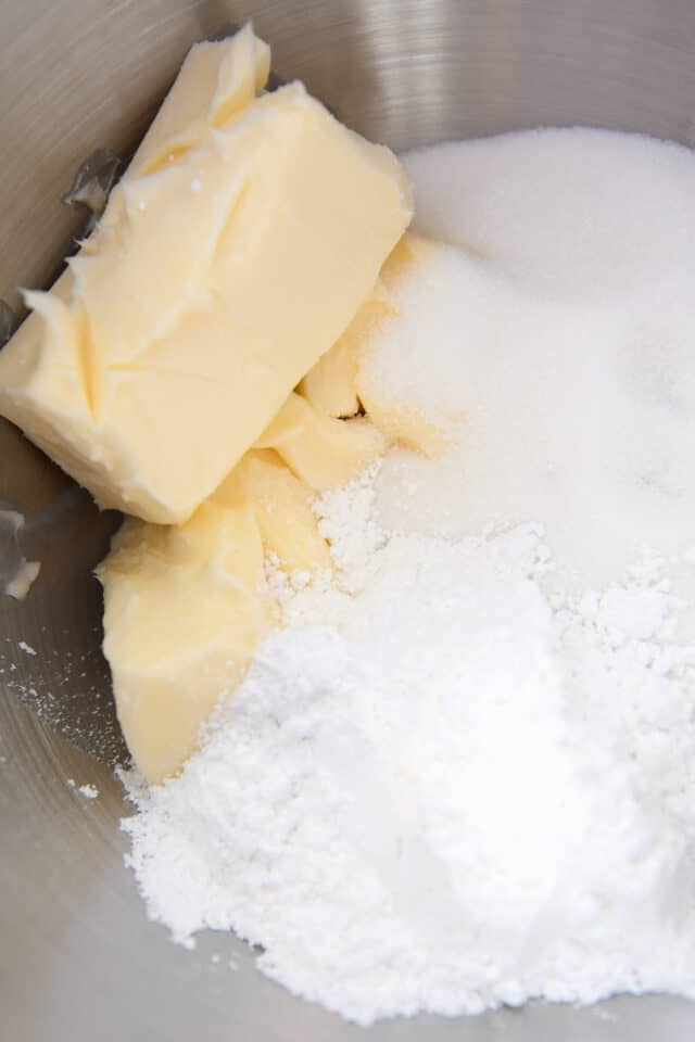 Butter, granulated sugar and powdered sugar in stainless bowl.