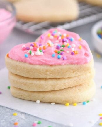 Frosted sugar cookie stacked on two unfrosted sugar cookies.