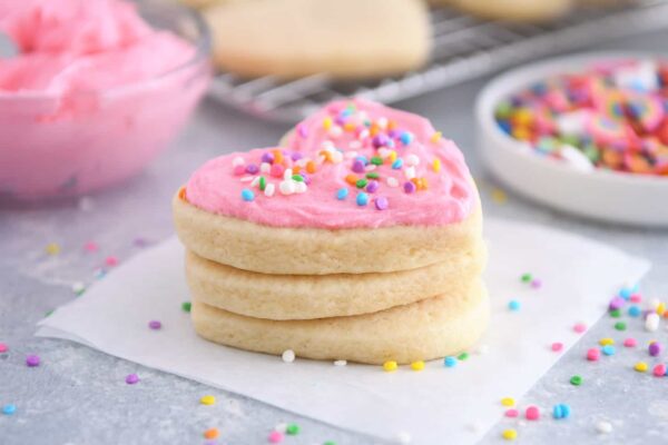 Frosted sugar cookie stacked on two unfrosted sugar cookies.