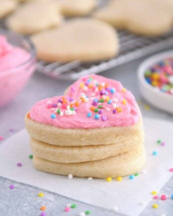 Heart shaped sugar cookie with pink frosting and sprinkles.
