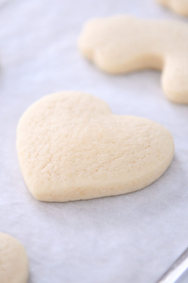 Heart shaped sugar cookie on parchment lined baking pan.