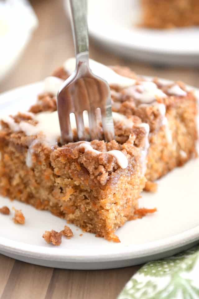 Fork scooping corner bite from square of carrot cake coffee cake.