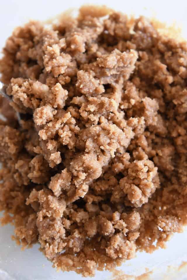 Mixed brown sugar and flour streusel with butter in glass bowl.