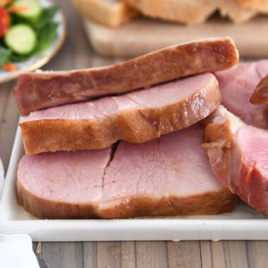 Several thick ham slices on white platter.