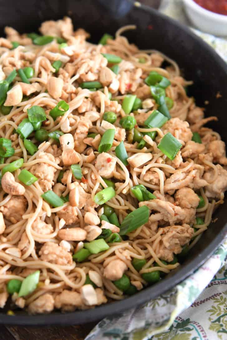 Ramen noodles with peas, green onions, ground turkey and cashews in cast iron skillet.