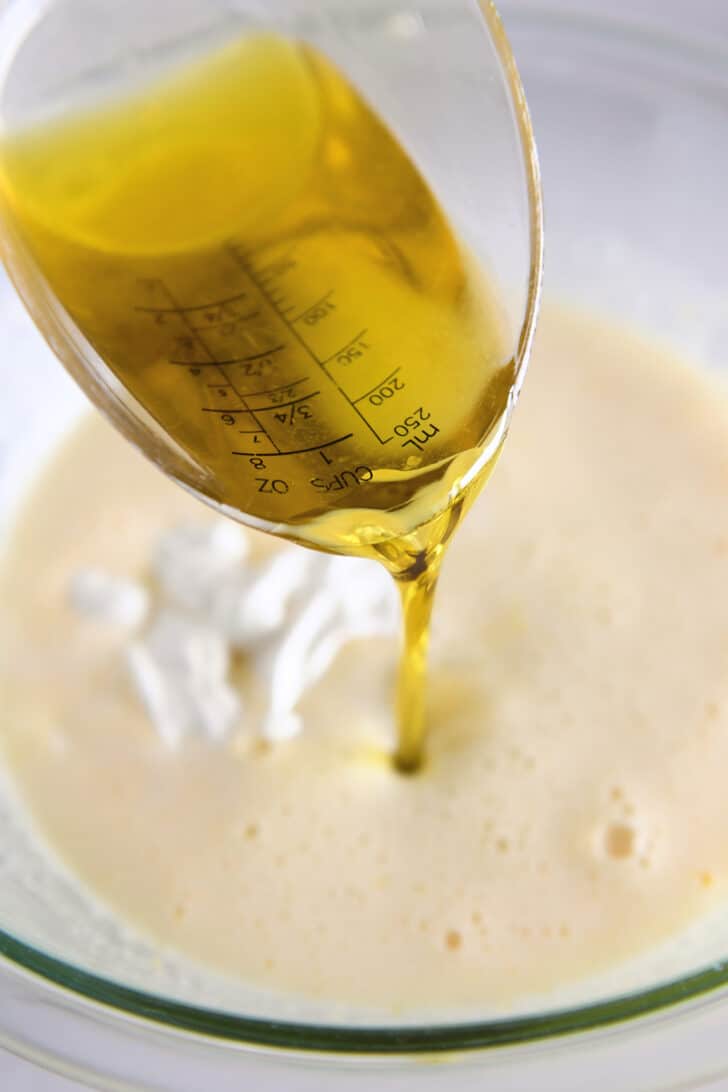 Pouring olive oil into bowl with cake batter ingredients.