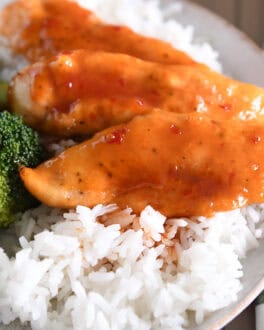 Plate with broccoli, rice and saucy chicken tenders.