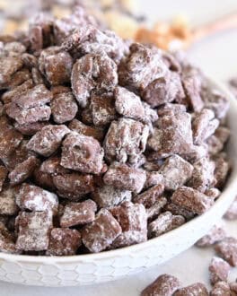 White bowl filled with towering pile of peanut butter and chocolate coated chex cereal.