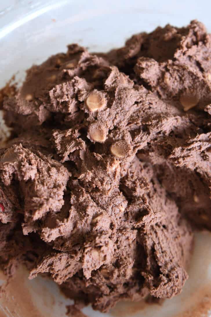 Chocolate cookie dough with peanut butter chips in glass bowl.