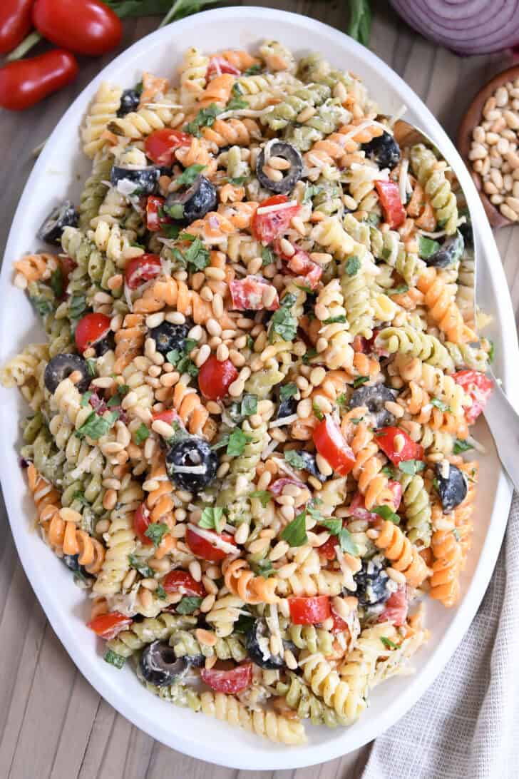 Top down view of colorful tri-color pasta salad on oval white platter.