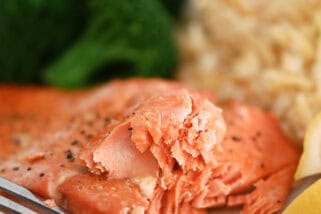 Salmon on gray plate with fork, rice pilaf and cooked broccoli.