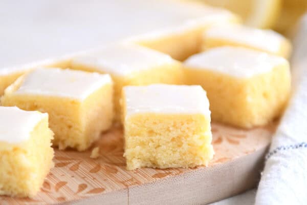 Lemon brownie squares with a white glaze on a wooden cutting board.