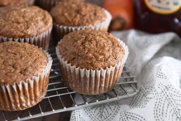 Several baked carrot cake muffins on wire cooling rack.