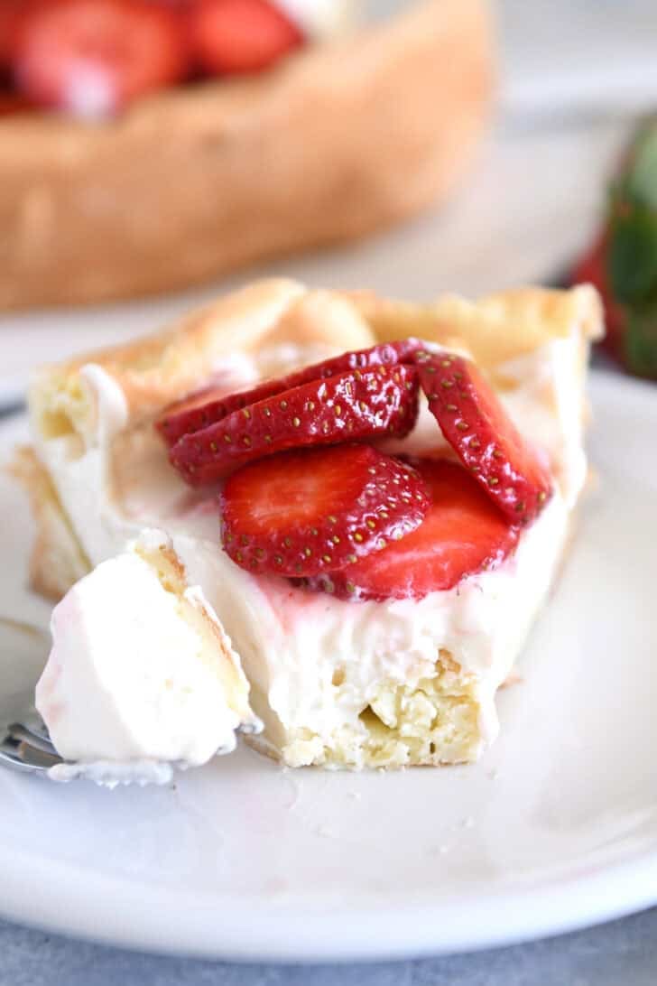 Slice of cream puff cake on white plate with one bite on fork.