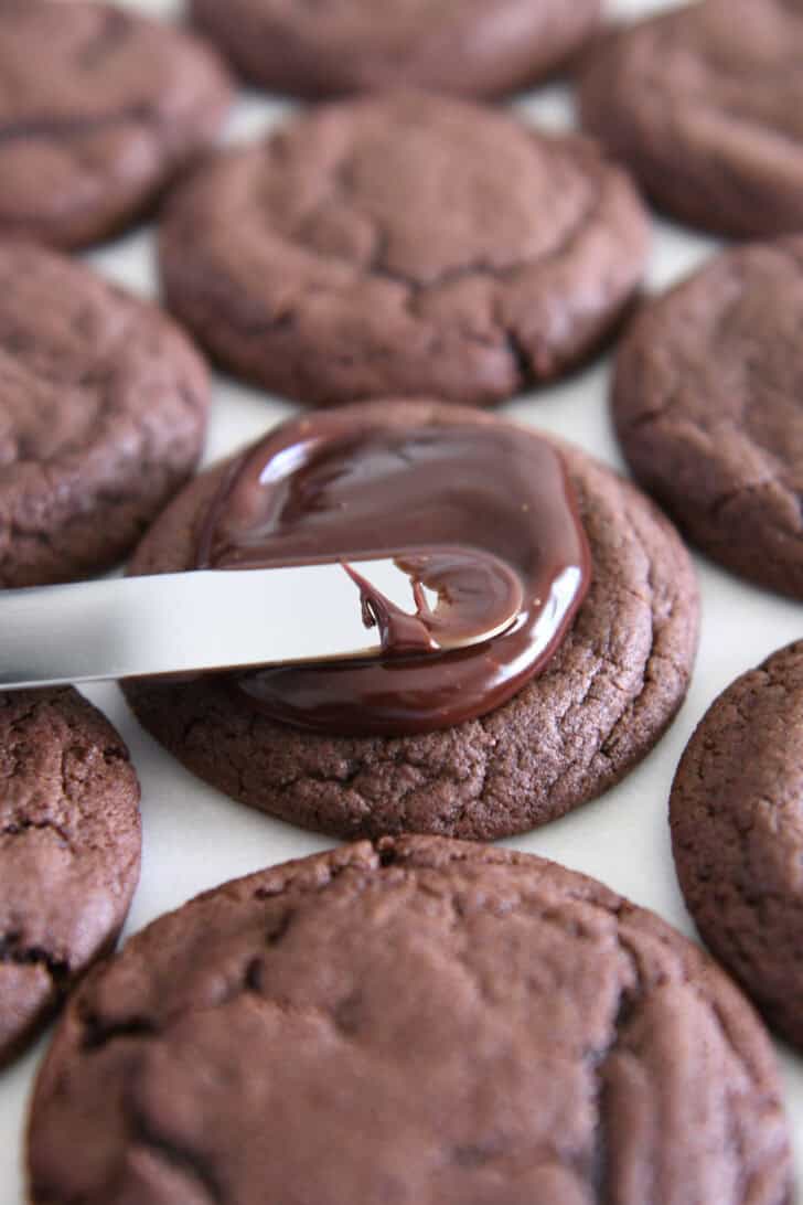 Spread the chocolate Ganache on the Fudgy Brownie Cookies with an offset spatula.