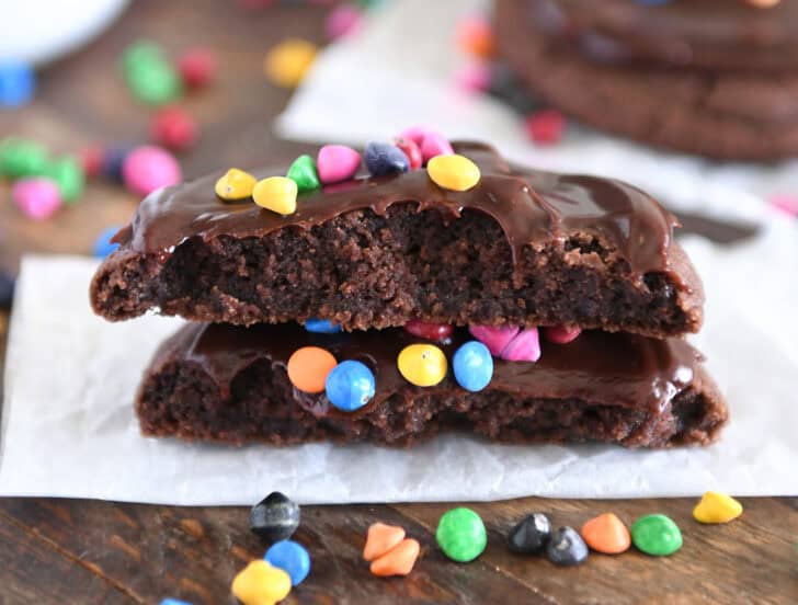 Cosmic brownie cookie in half and stacked on white parchment paper.