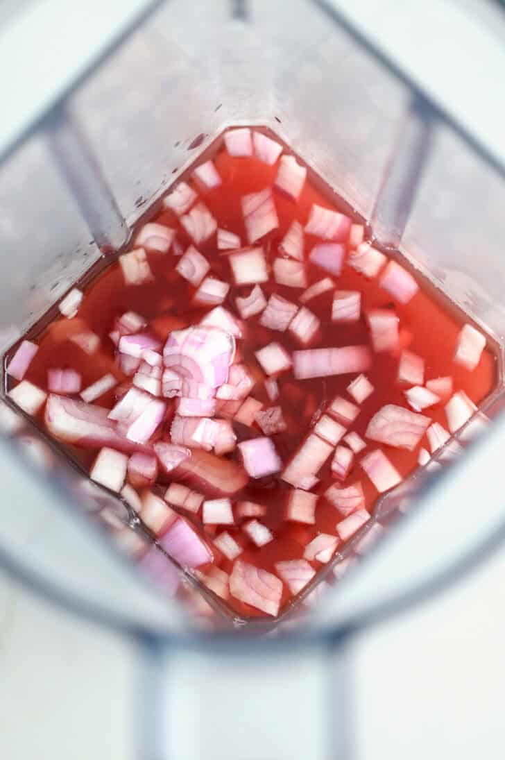 Top down view of blender with onions, red wine vinegar and olive oil.