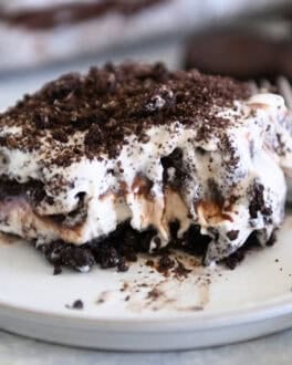 Square of layered Oreo ice cream dessert on gray plate with bite taken out.