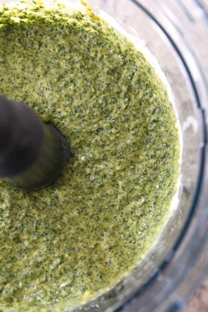 Top down view of pesto in a food processor.