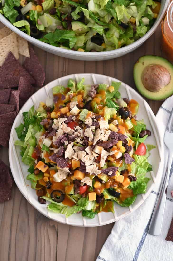 Top down view of White ridged plate with chopped taco salad and drizzled with homemade catalina dressing.