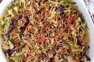 Asian chicken salad topped with chow mein noodles in white bowl.