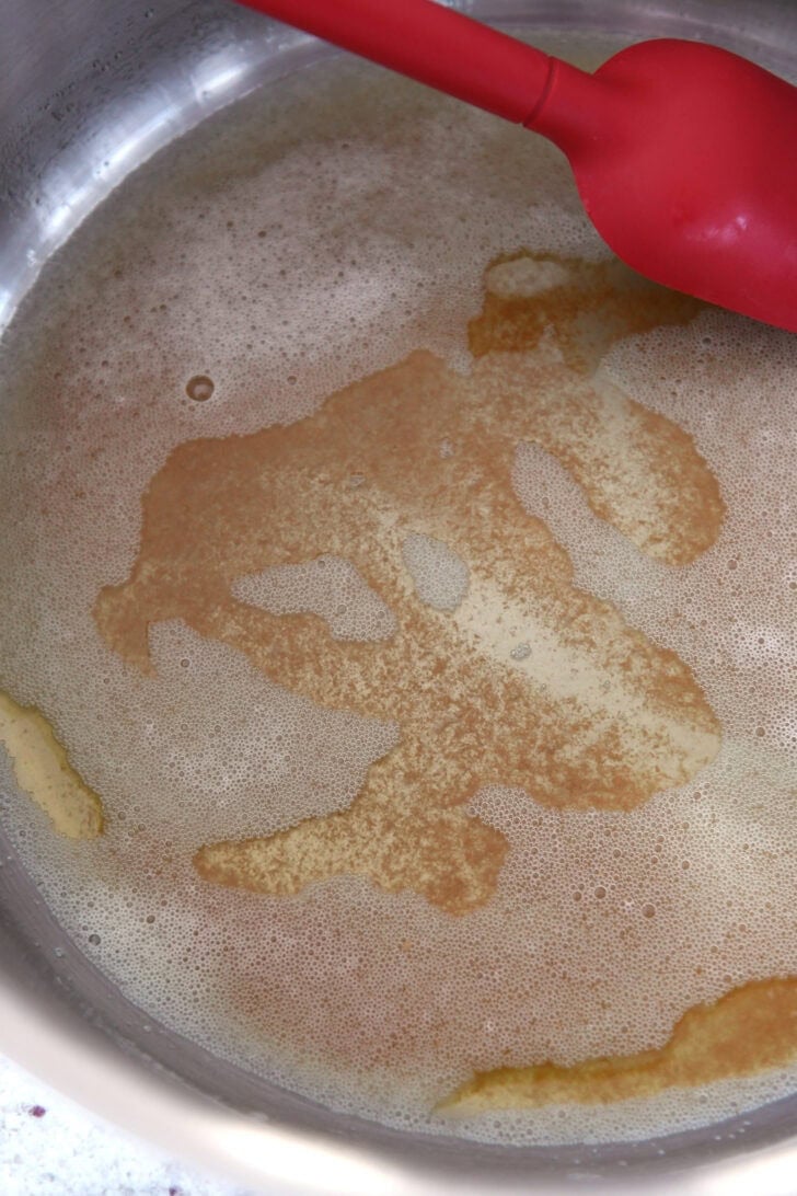 Top down view of butter being browned in a metal pot.
