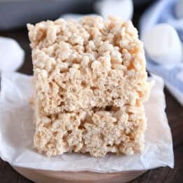 Two rice krispie treats stacked on top of each other on a piece of parchemtn paper.