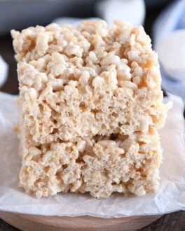 Two rice krispie treats stacked on top of each other on a piece of parchemtn paper.