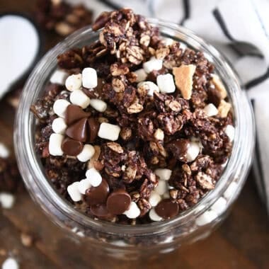 Top down view of glass jar filled with chocolate granola, graham cracker pieces and mini marshmallows.