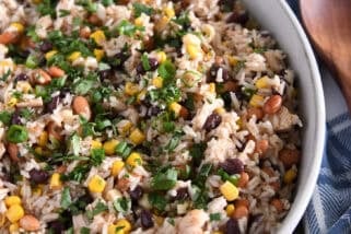 Top down view of a white oval dish with a rice, bean, and chicken salad topped with chopped cilantro.