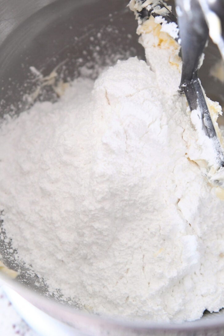 Top down view of a metal bowl with powdered sugar and butter.