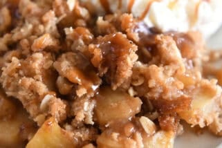 Serving of caramel apple crisp on gray plate with scoop of ice cream.