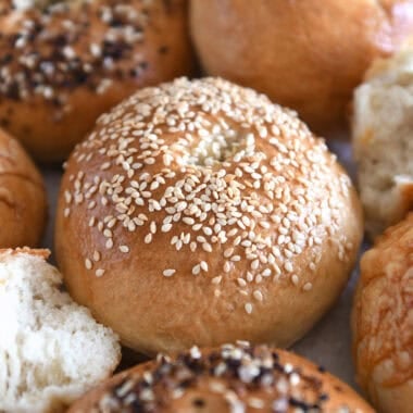 Sesame seed topped bagel with several other baked bagels.