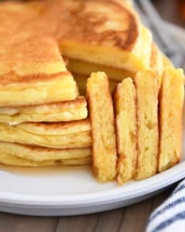 Four triangle slices cut out of stack of four pancakes on gray plate.