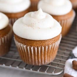 Many Pumpkin Cupcakes are arranged with Whed Cream Cheese Frosting on a Wire Cooling Rack.