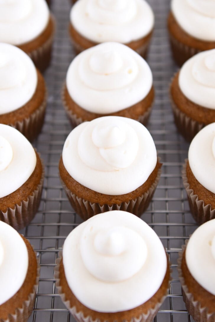 Many pumpkin pies are arranged with Cream Cheese Frosting on a Wire Cooling Rack.