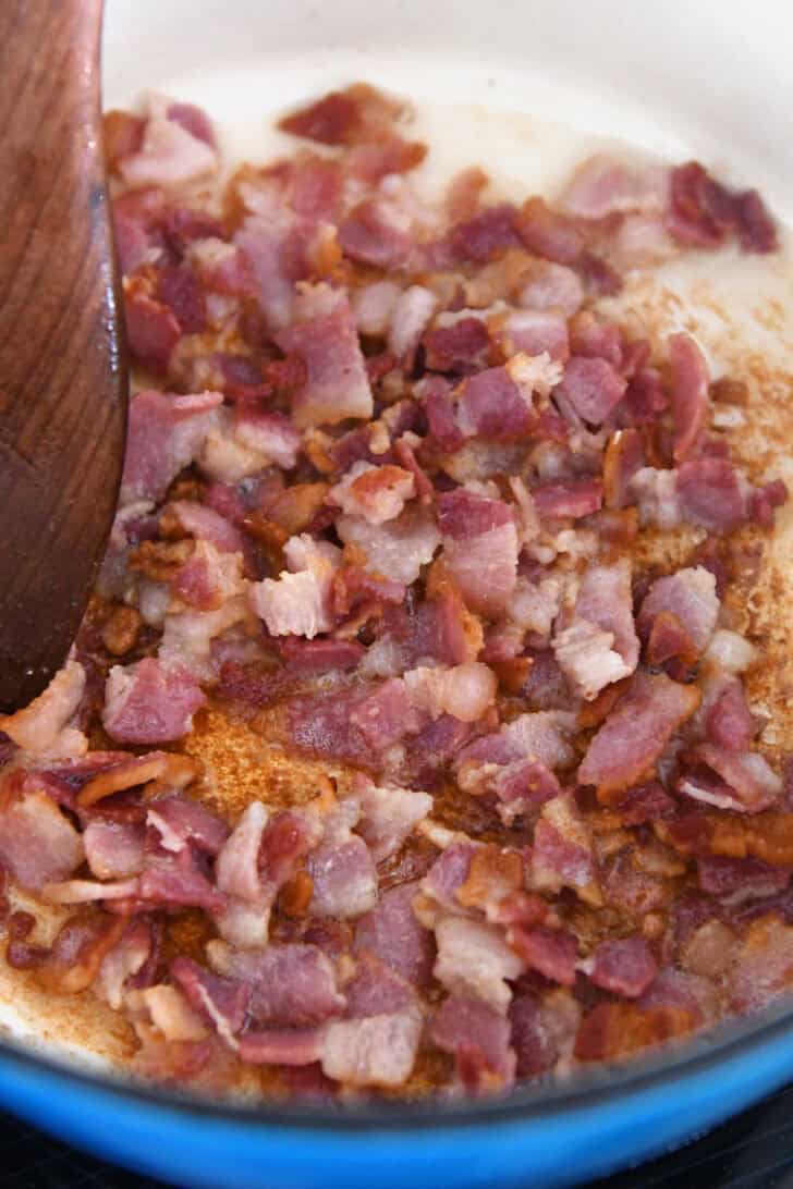 Top down view of a pot cooking small pieces of bacon.