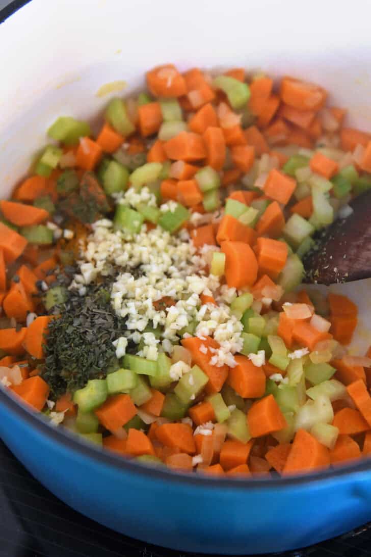 Cast iron pot with celery, carrots, onions, dried basil, and garlic.