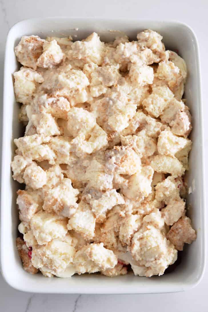 Cream-covered angel food cake cubes on top of whipped cream and cranberry orange mixture.