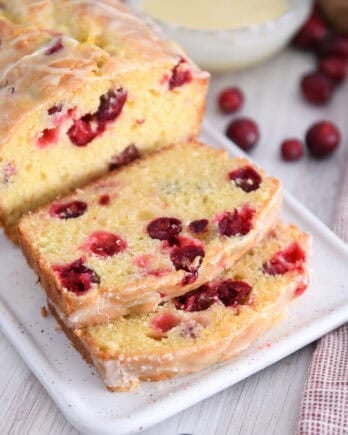 Two slices cut from cranberry orange loaf on white tray.