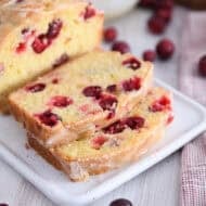 Two slices cut from cranberry orange loaf on white tray.