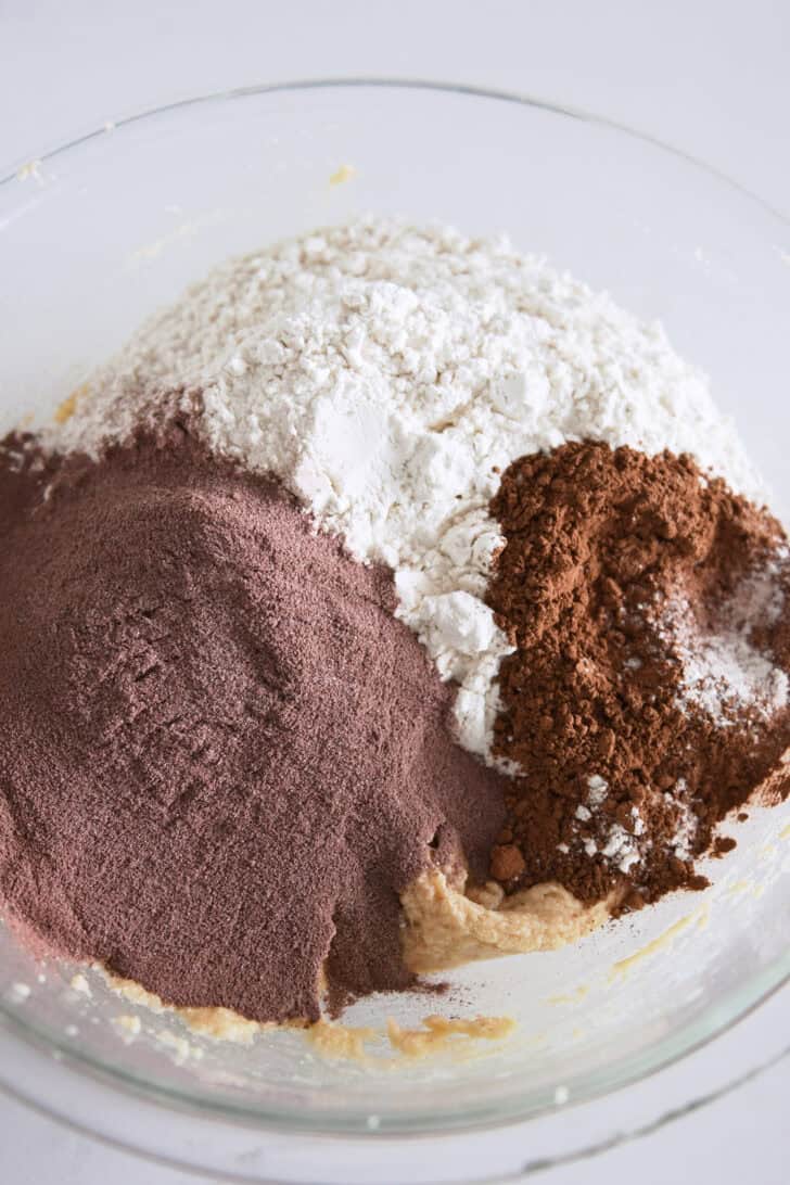 Glass bowl with cookie dough, flour, hot cocoa mix, cocoa powder.