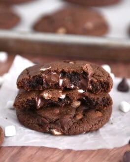 Two half chocolate cookies with gooey melted chocolate chips and mini marshmallows stacked on one full cookie.