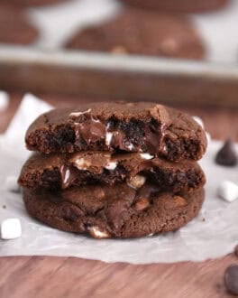 Two half chocolate cookies with gooey melted chocolate chips and mini marshmallows stacked on one full cookie.