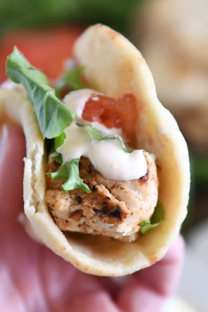 A flatbread grilled chicken wrap with lettuce, tomato, and a creamy sauce.