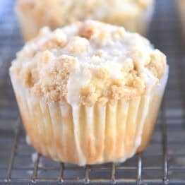 Lemon muffins with crumb toppings and white glaze on a cooling rack.