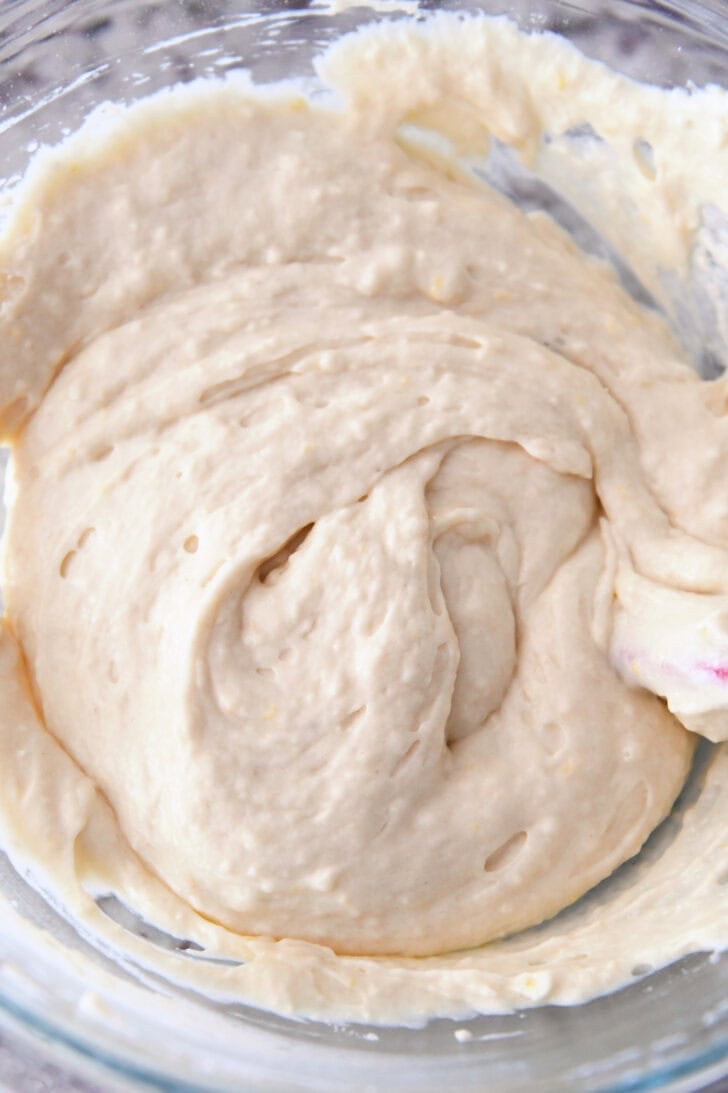 Top down view of lemon muffin batter in a glass bowl.