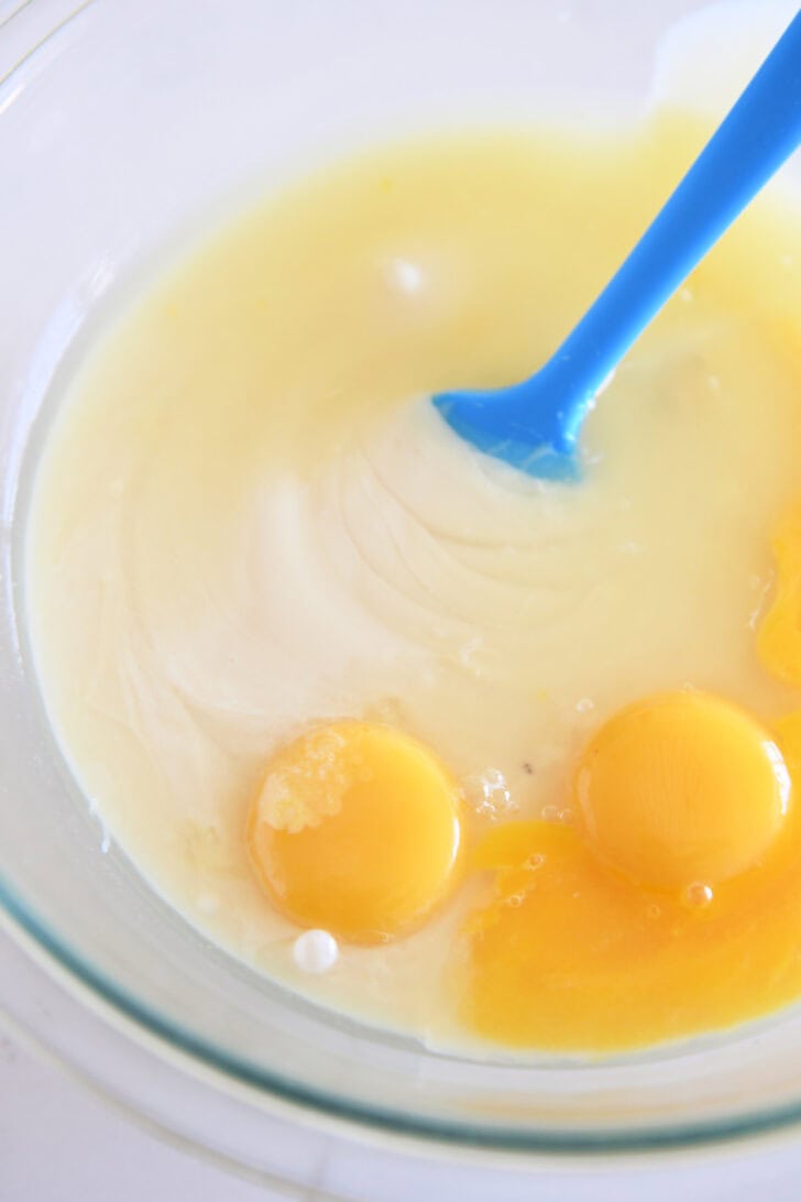 Top down view of a glass bowl with a lemon filling and raw eggs.